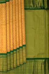 Light Orange Kanchipuram Tissue Silk Saree embossed, and intricately designed silver and gold butta on the body with leaf green contrast border and annam, grand, kuyil kan designs in pallu